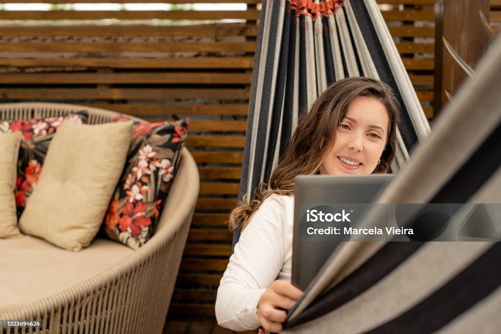 Woman making video call on laptop sitting in hammock Woman working on laptop sitting  in hammock Convenience Stock Photo