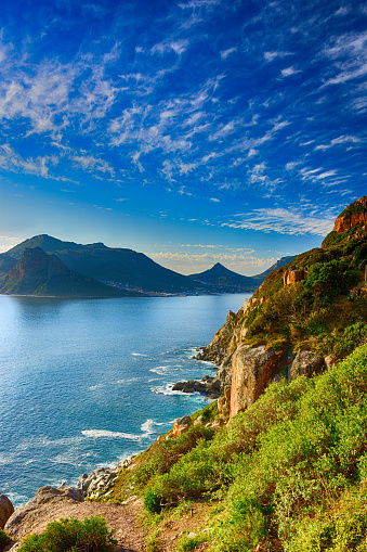 South Africa Hout Bay Cape Town golden hour scenic, peaceful and romantic panoramic landscape and seascape with golden sunset, blue quiet sea, mountains and a blue sky with clouds, harmony, panorama