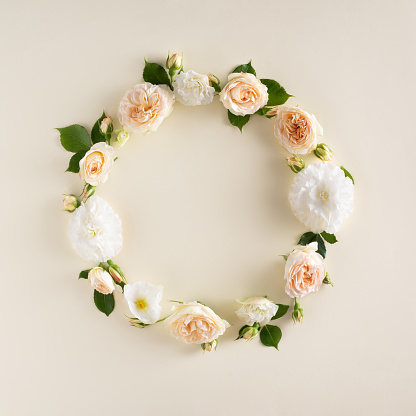 Summer wreath made of roses and leaves isolated on a cream background. Natural round frame layout. Flat lay, top view.