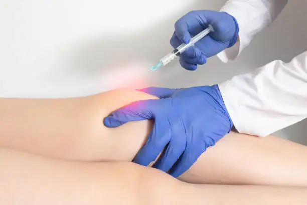 Photo of The doctor injects an ozone-oxygen mixture into the patient's knee joint to relieve muscle spasm and inflammation. Ozone therapy, copy space for text