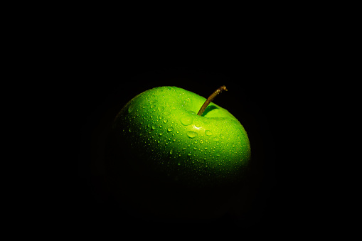 Close-up of a green apple with a black background