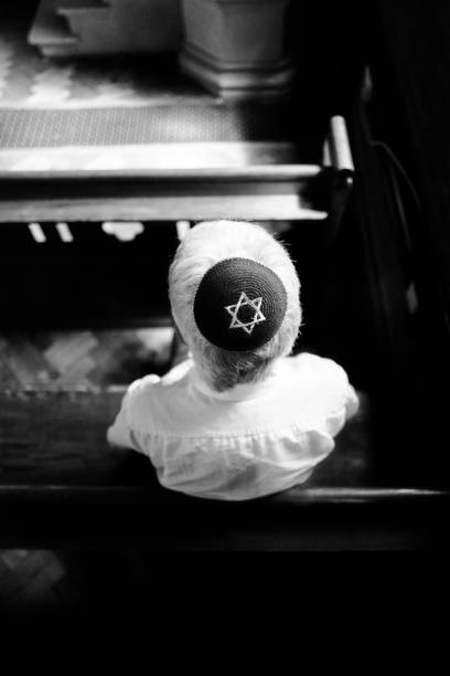 istock Senior Jewish man wearing skull cap praying inside synagogue 1323705080