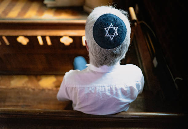 istock Senior Jewish man wearing skull cap praying inside synagogue 1323705161