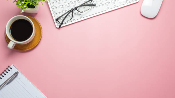 istock Desk with coffee keyboard notebook glasses on pink background. Copy space. 1323705374