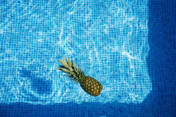 istock Pineapple floating on wavy water surface of swimming pool. background. summer concept. 1323710636