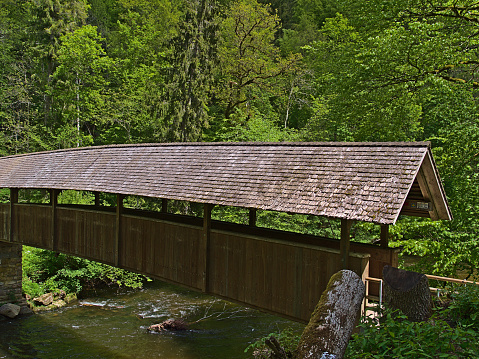 Covered wooden footbridge crossing a river in famous Wutach Gorge (