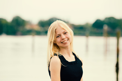 Blond girl standing smiling at the camera outdoors