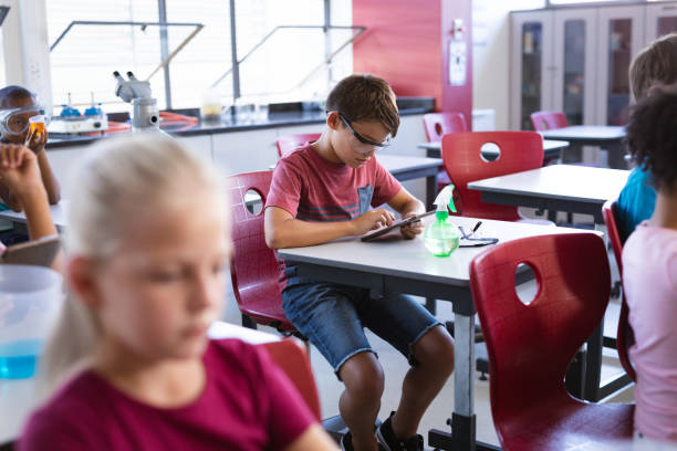 istock Caucasian boy wearing protective glasses using digital tablet in science class at laboratory 1323715730