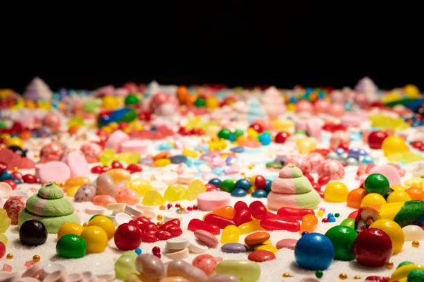Confectioner’s close up of jelly beans, colorful chocolate coated candy, various flavours mixed sweets, marshmallow, snack, caramels, swirls, sugar and cake sprinkles. Candy land explosion dream.