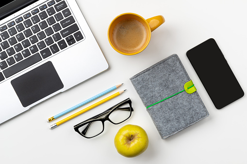 Flat lay top view modern laptop, food and stationery on white table. Back to school work from home concept