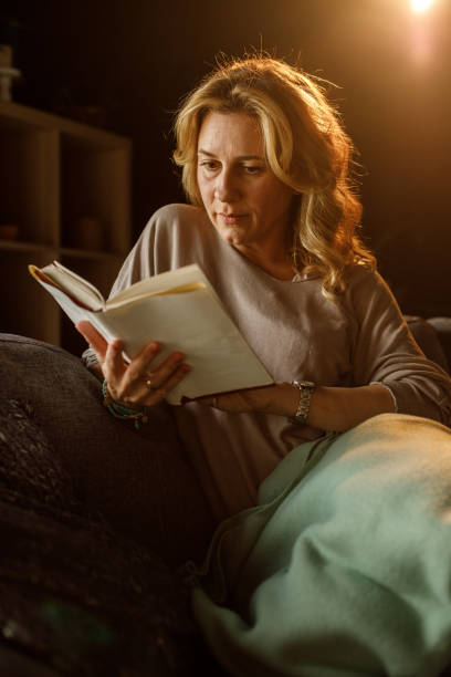 istock Woman relaxing on sofa after a long day, enjoying reading a book 1323731977
