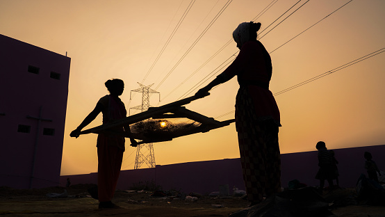 Dumka, Jharkhand, India - November 24 2020: Two Indian woman worker working at the construction site, the silhouette of women working