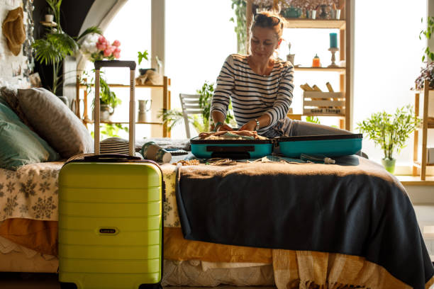 istock Woman arranging cloths in a suitcase she is packing for vacation 1323734959