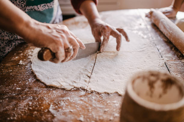istock Woman cutting a stretched dough for rolls 1323736388