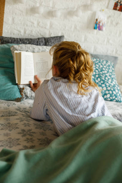 istock Woman lying in bed and reading a book 1323736572