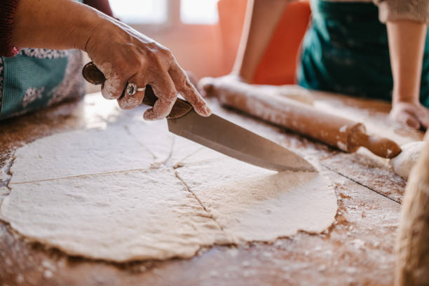 istock Woman cutting a stretched dough for rolls 1323736596
