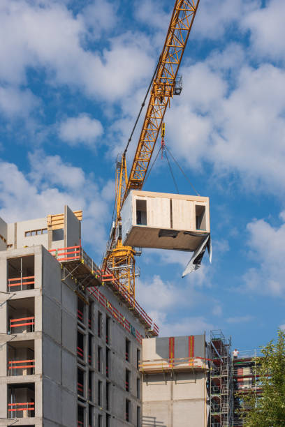 istock Crane lifting a prefabricated wooden building module to its position in the structure. 1323737167
