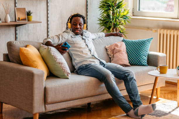 istock Handsome man enjoying music at home and texting on phone 1323738184