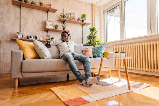 istock Handsome man enjoying music at home and texting on phone 1323738211