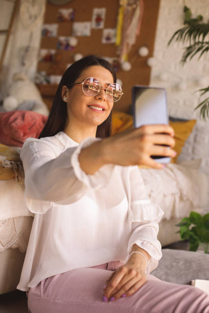 istock Smiling young woman taking selfies with smart phone 1323738368
