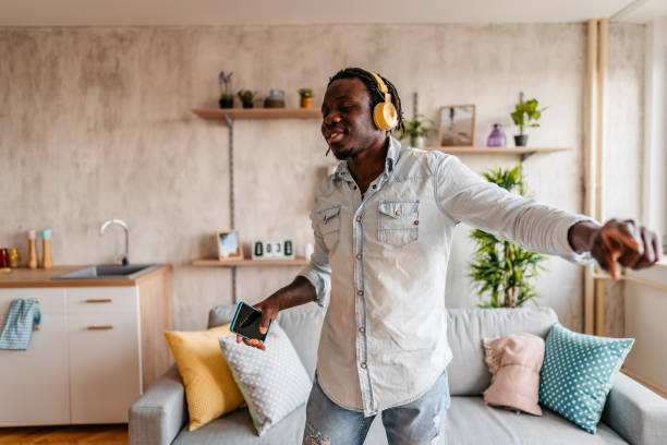 istock Man holding phone singing and dancing at home 1323739659