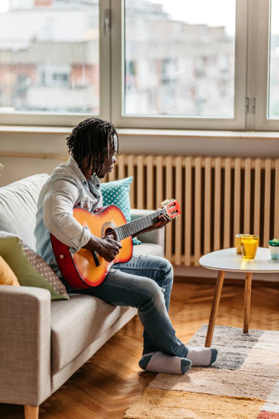 istock Man playing acoustic guitar at home 1323740063
