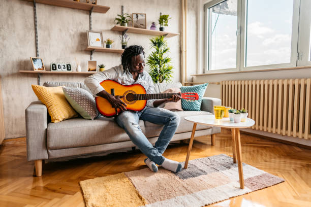 istock Man playing acoustic guitar at home 1323740184