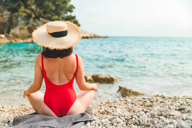 istock woman sitting on blanket at sea beach 1323740955
