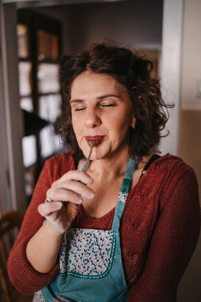 woman licking the spoon with chocolate cream - pampering imagens e fotografias de stock