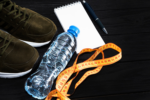 sneakers and a bottle of water on a black wooden background. The concept of a healthy lifestyle.