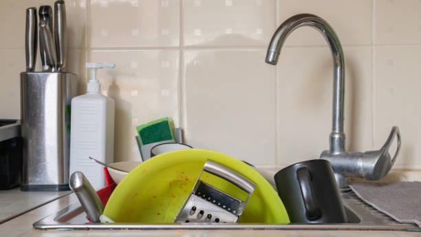 os utensílios de cozinha na bacia de lavagem precisam ser lavados. uma pilha de pratos sujos na pia da cozinha. utensílios de cozinha precisam ser lavados. conceito de lição de casa. - domestic kitchen kitchen sink house home interior - fotografias e filmes do acervo