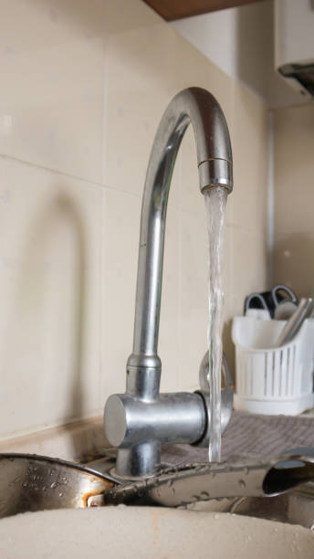 the kitchen utensils in the wash basin need to be washed. a pile of dirty dishes in the kitchen sink with running water. kitchen utensils need washing. homework concept. - sink domestic kitchen kitchen sink faucet imagens e fotografias de stock