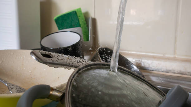 the kitchen utensils in the wash basin need to be washed. a pile of dirty dishes in the kitchen sink with running water. kitchen utensils need washing. homework concept. - sink domestic kitchen kitchen sink faucet imagens e fotografias de stock