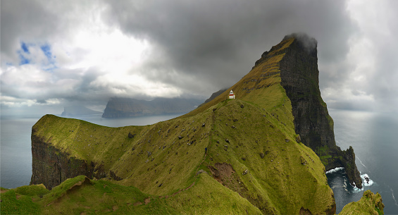 Panoramic view of Kallur Lighthouse at Kalsoy Island on a cloudy day with dramatic skies on Faroe Islands, Denmark.