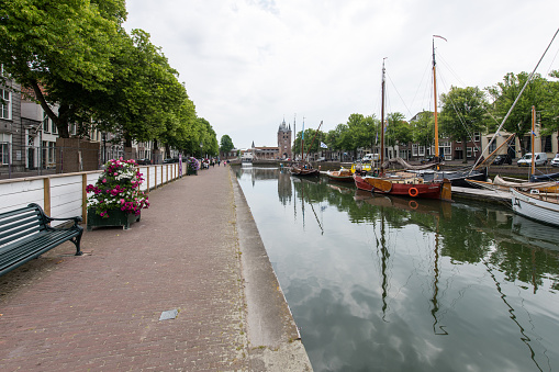 The old harbor with traditional sailing ships in Zierikzee in the Dutch province of Zeeland. Fortified city wall, city gate and tower are visible in the background.