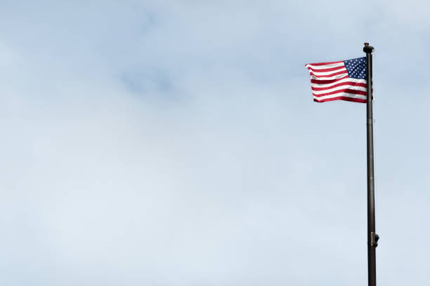 istock Sunlit American Flag Waving in the Wind on a Flagpole 1323750480