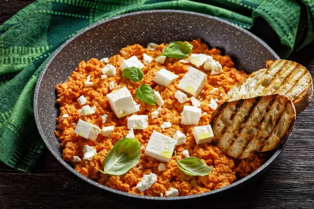 Strapatsada, eggs scrambled with tomatoes and feta cheese in a skillet with toasted bread, horizontal view, greek cuisine