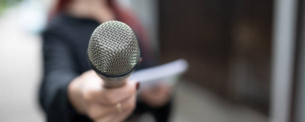 istock Say! Journalist at news conference, writing notes, holding microphones 1323756492