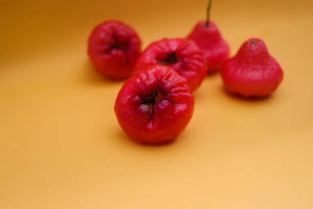 istock Freshly rose apple fruit isolated on orange background. Also known as jambu air Merah (Syzygium aqueum), jambu Semarang (Syzygium samarangense), Jambu Bol, or Malay Apple (Syzygium malaccense) 1323756850