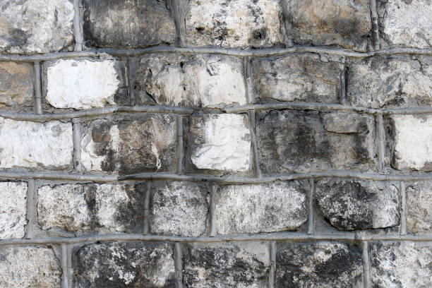 istock Old wall made of rough stone blocks with decorative concrete borders between rocks 1323757619