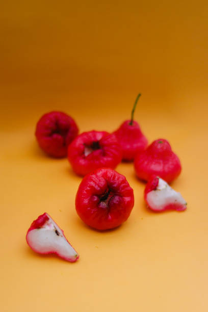 istock Freshly rose apple fruit isolated on orange background. Also known as jambu air Merah (Syzygium aqueum), jambu Semarang (Syzygium samarangense), Jambu Bol, or Malay Apple (Syzygium malaccense) 1323757895