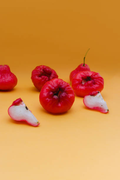 istock Freshly rose apple fruit isolated on orange background. Also known as jambu air Merah (Syzygium aqueum), jambu Semarang (Syzygium samarangense), Jambu Bol, or Malay Apple (Syzygium malaccense) 1323759400