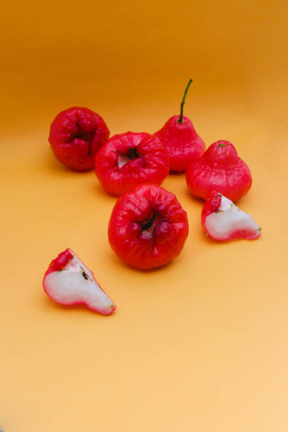 istock Freshly rose apple fruit isolated on orange background. Also known as jambu air Merah (Syzygium aqueum), jambu Semarang (Syzygium samarangense), Jambu Bol, or Malay Apple (Syzygium malaccense) 1323759482