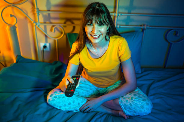 istock Smiling woman watching TV at night 1323760509