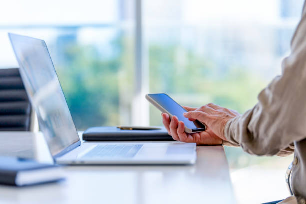 Close up of a businessman using a laptop computer and a mobile phone.