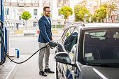 Happy young man refueling his car the gas station.