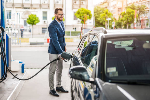 счастливый молодой человек заправляет свою машину на за�правке. - gasoline filling gas station car стоковые фото и изображения