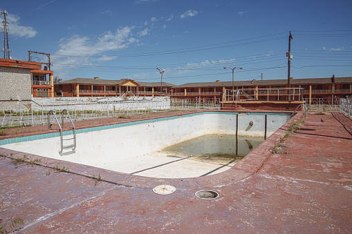 Clinton, Oklahoma - May 6, 2021: Dirty abandoned outdoor swimming pool at the Glancy Motel rooms, now abandoned, along the historic US route 66