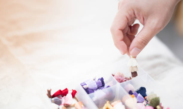 istock Hand holding multicolor tassel choosing for decorating with many things as earring pendant or decorate with the leather bag, The tassel put on the plastic box. 1323771711