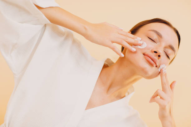 istock Young woman applying cosmetic white cream on her face 1323773269